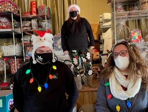 Three people wearing Christmas attire and masks. 