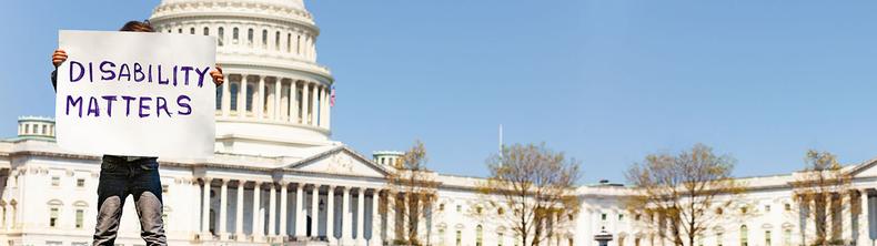 A person stands in front of the U.S Capitol with a sign that reads Disability Matters.