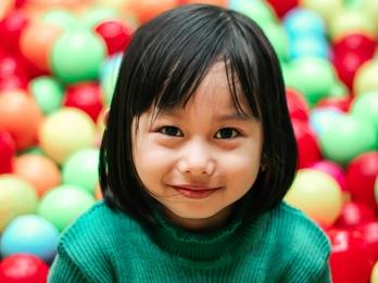 A girl smiling in a ball pit.