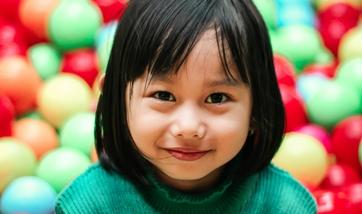 A girl smiling in a ball pit.